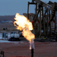 A natural gas flare in front of pump jacks.